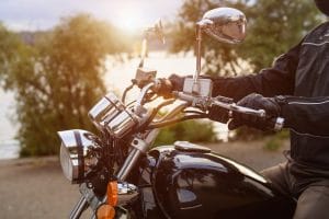 Biker riding on motorcycle near the river in the city. Close-up of handlebar